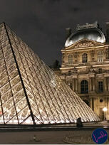 The glass pyramid at the Louvre in Paris lit up at night with historic architecture behind it