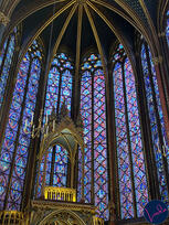 Stained glass windows inside Sainte-Chapelle in Paris, with vibrant colors and ornate Gothic architecture.