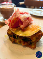 A decadent croque madame topped with a fried egg, ham, and shaved cheese, served with a latte at Buvette café in Paris.